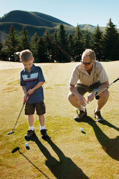 Grandfather Teaching Golf To Boy