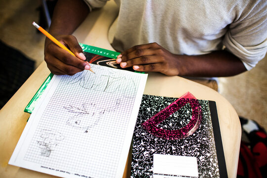 High angle view of teenage boy drawing on graph paper in classroom