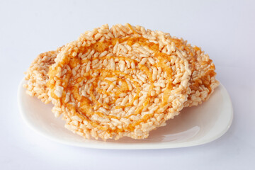 Thai sweet crispy rice cakes with cane sugar drizzle Thai people call Khaotan in white plate.