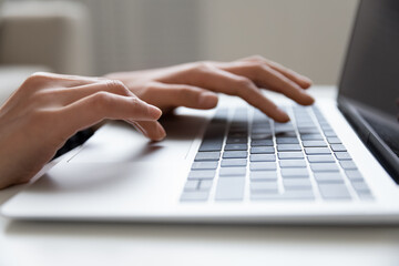 Close up of young female hands typing on keyboard of modern laptop computer browse internet search data information on web. Cropped shot of millennial woman pc user work on distance online communicate