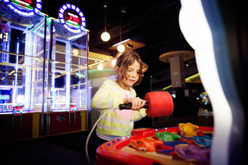 Girl playing game at amusement arcade
