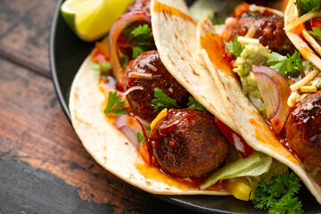 Meat free beetroot and pea protein meatballs taco wraps with avocado guacamole, sweet chilli sauce and lime wedges