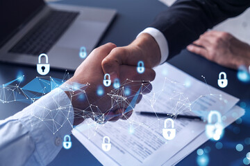 Handshake of two businessmen who enters into the contract to protect cyber security of international company. Padlock Hologram icons over the table with documents.
