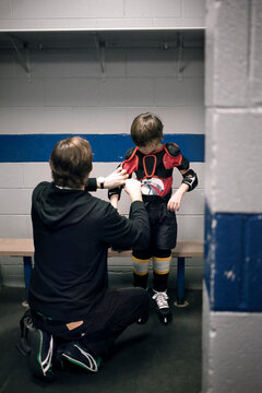 Father helping son with ice hockey uniform