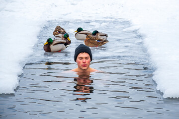 Beautiful boy bathing and swimming in the cold water of a lake or river among the ducks, cold...