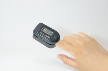 指に付けたパルスオキシメーター。血中の酸素飽和度および心拍数を図れるデジタル表示できるディスプレイの計測器。