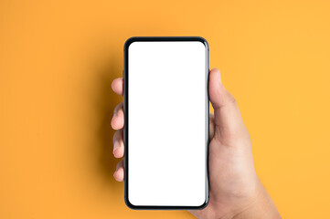 Close up of people hand holding smartphone with white blank screen on yellow background.