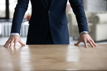 Crop close up of successful businessman in suit stand near table in office show power and...