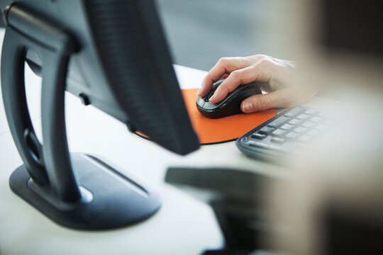 Cropped image of woman using computer at office desk