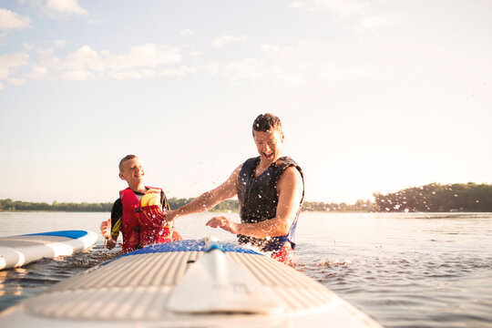 Father and son enjoying at lake against sky on sunny day