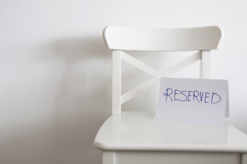 empty white chair with reserved sign