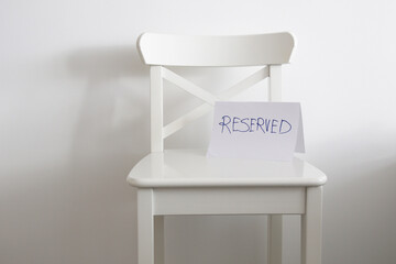 empty white chair with reserved sign
