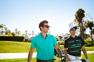 Happy golfers walking on field against clear sky