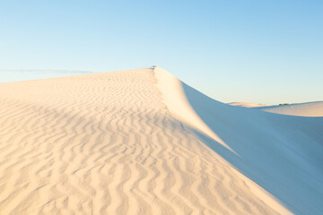 Fototapeta na wymiar White sand dunes against blue cloudless sky, Jurien Bay