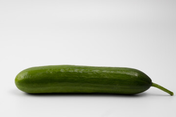 A ripe, green cucumber with stalk on a white background. Space for text