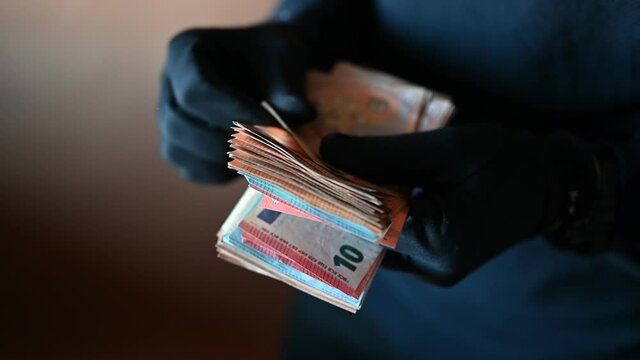 Closeup of hands with black gloves counting a handful of euro bills