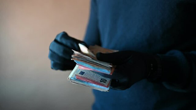 Closeup of hands with black gloves counting a handful of euro bills