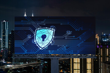 Padlock icon hologram on road billboard over panorama city view of Kuala Lumpur at night to protect business, Malaysia, Asia. The concept of information security shields.