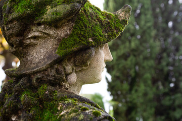 Close up of old statue overgrown with moss.