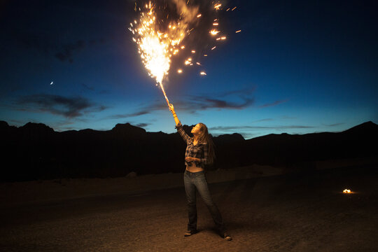 Woman burning fireworks on mountain against sky at dusk