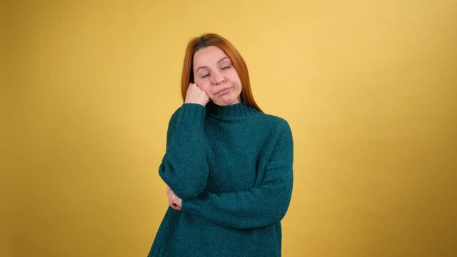 Lazy sleepy young woman standing leaning on hand, looking at camera with bored indifferent expression, exhausted of tedious communication. studio shot isolated on yellow background