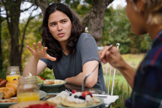 Man talking to friend while having breakfast outdoors