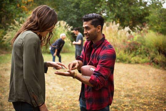 Friends discussing while playing football on field