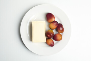 Plate with butter and palm oil fruits isolated on white, top view