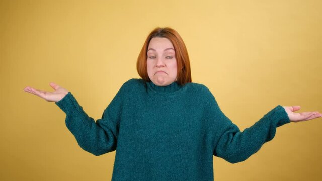 Don't know, who cares. Happy lovely beautiful woman shrugging shoulders, looking with uncertain clueless expression, demonstrating indifference doubts. indoor studio shot isolated on yellow background