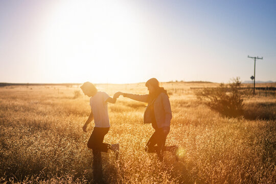 Couple walking while holding hands on field against clear sky