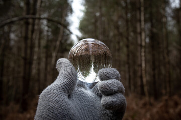 Lens Ball held by gloved hand in English forest on a grey day. Lensball optics dark dramatic...