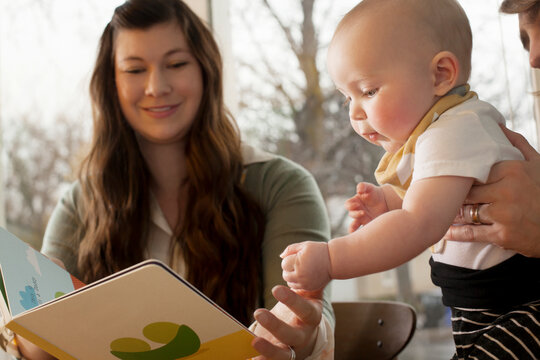 Mother showing picture book to baby at home