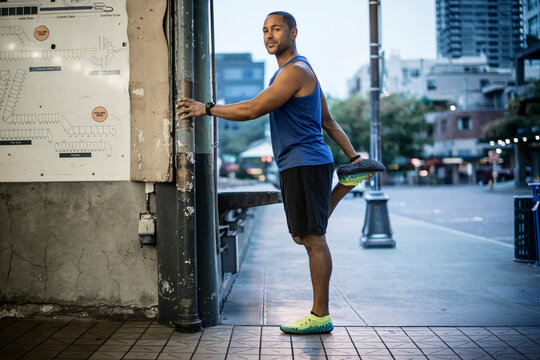 Portrait of man stretching leg at street