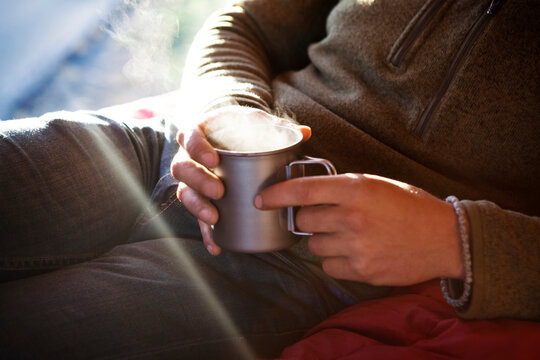 Midsection of man holding dink while sitting on bed in camper van