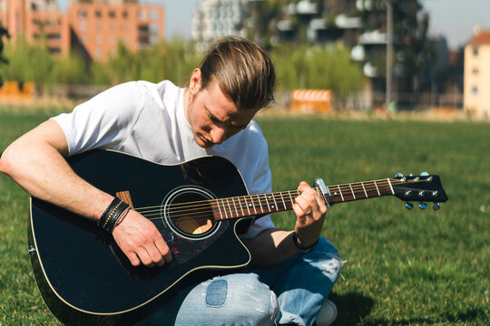 Young singer play the guitar in a garden during a sunny day