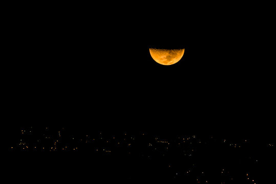 Half moon set over the city at night