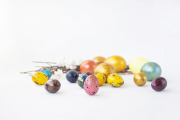 There are many colorful eggs on a white background. Holiday and joy of Bright Easter for the whole family. Small and large shiny eggs. Real hand-painted eggs. Multifaceted photo.