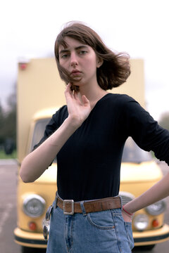 Portrait of confident young woman with hand in back pocket standing against truck