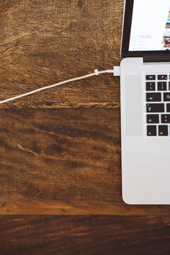 High angle view of laptop computer with USB cable on wooden table