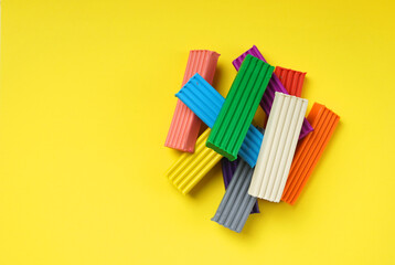 Children's colorful plasticine bricks on a yellow background. Copy space. - obrazy, fototapety, plakaty
