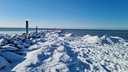 Winter landscape by the sea on a sunny winter day. Ice and blue sky. Natural winter landscape