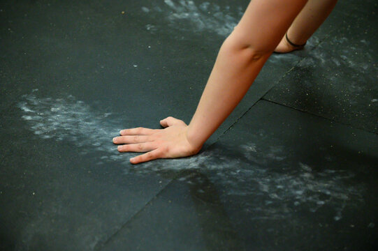 A woman's arms and hands on a chalked up floor during crossfit.