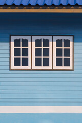 Sunlight on surface of 3 white windows on blue wooden wall of the old vintage house in vertical frame
