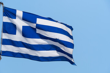 Greek flag waving on the blue sky background. National symbol of Greece, waving flag.