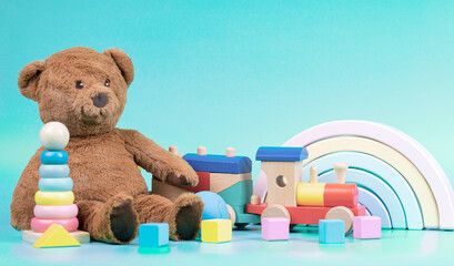Kids toys collection. Teddy bear, wooden rainbow, train and baby toys on light blue background