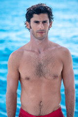 Portrait of handsome man, shirtless surfer with and blue ocean on background in Maldives