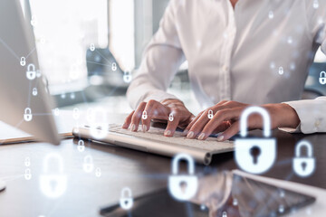 A woman programmer is typing a code on computer to protect a cyber security from hacker attacks and save clients confidential data. Padlock Hologram icons over the typing hands. Formal wear.