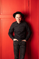 Man in black shirt and hat on red background