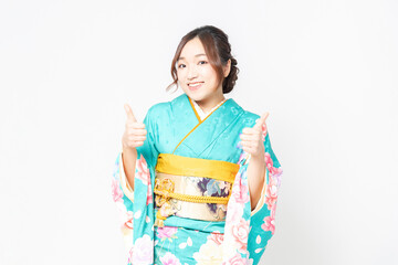 白背景の前に立って、いいねのジェスチャーをする振袖を着た女性
