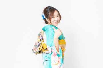 白背景の前に立って、いいねのジェスチャーをする振袖を着た女性